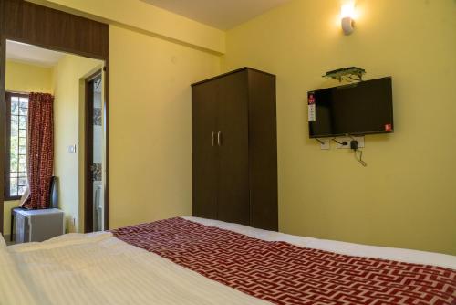 a bedroom with a bed and a tv on the wall at VGR-HOMESTAY in Kodaikānāl