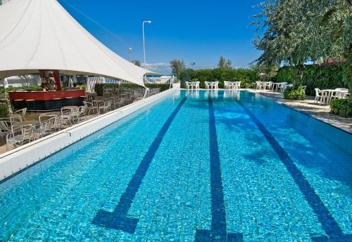 a large swimming pool with chairs and a white tent at Hotel Mareblu in Senigallia