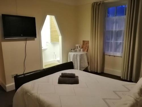 a bedroom with a bed with a television and a table at The Parkers Arms - The home of Cattlemans Steakhouse in Paignton