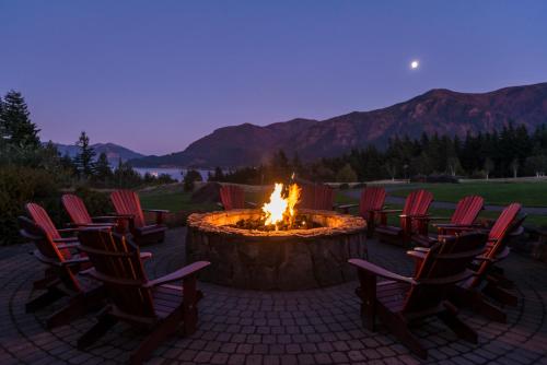 a fire pit with chairs around it with mountains in the background at Skamania Lodge in Stevenson