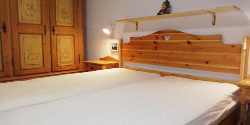 sypialnia z dużym białym łóżkiem z drewnianym zagłówkiem w obiekcie CasaMau Trilo w mieście Campitello di Fassa