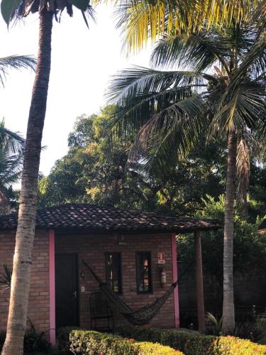 a small house with two palm trees in front of it at Pousada do Riacho in Barreirinhas