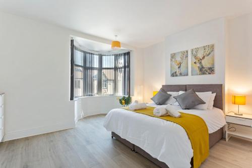 a white bedroom with a large bed and a window at Jasmine Villa A - Ideal for QMC & Uni - Free parking in Nottingham