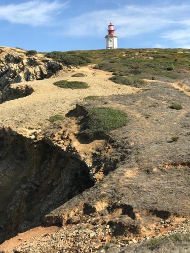 a lighthouse on top of a hill with rocks at O Pátio in Fernao Ferro