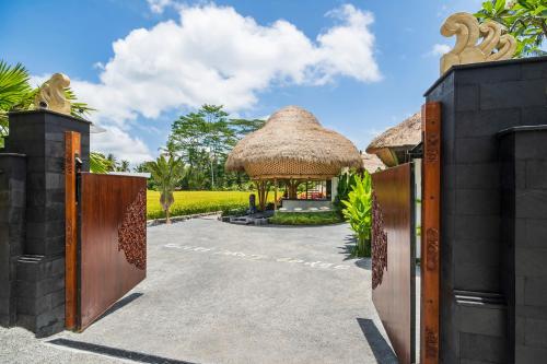 a gate leading to a villa with a thatched roof at Keliki Luxury Lodge in Ubud
