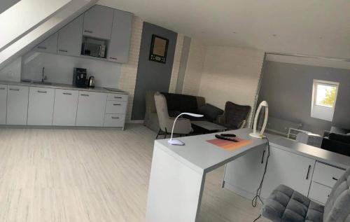 a living room with a white desk and a kitchen at Apartament Centrum Mazury - Szczytno in Szczytno
