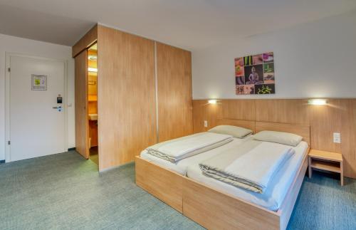 a bedroom with a large bed with a wooden headboard at Motel Hohenems in Hohenems