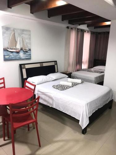 a room with two beds and a red table and a red chair at Apartamento Edificio Bahía Fragata in San Andrés