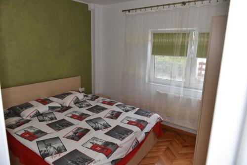 a bedroom with a bed with a blanket with photos on it at Apartament Stefan in Băile Govora
