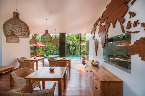 a dining room with tables and chairs and a pool at Keliki Luxury Lodge in Ubud