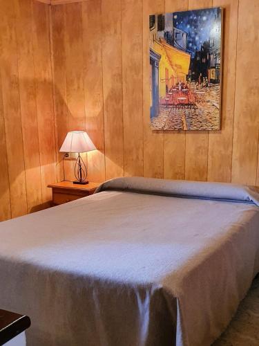 a bedroom with a bed and a painting on the wall at Complejo Turístico Las Cañadas Casas de Campo- Actividades Gratuitas Todos los Fines de Semana in Baños de Montemayor