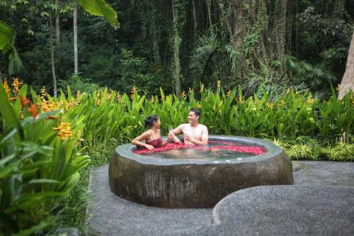 two young boys sitting in a fountain in a garden at Keliki Luxury Lodge in Ubud