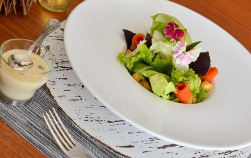 a white plate with a salad and a glass of milk at Capão do Cerrado Pousada e Spa in Itabirito