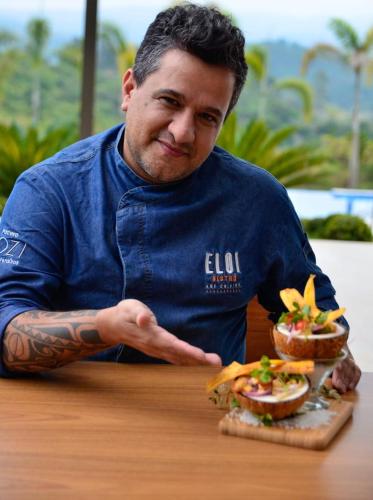 a man sitting at a table with a sandwich at Capão do Cerrado Pousada e Spa in Itabirito
