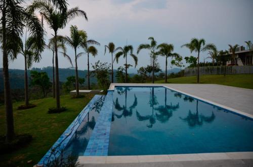 a swimming pool with palm trees in the background at Capão do Cerrado Pousada e Spa in Itabirito