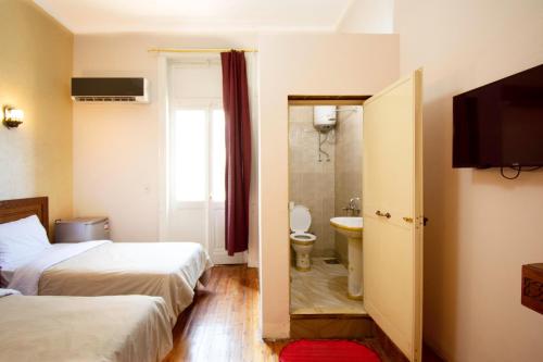 a hotel room with two beds and a bathroom at Minerva Grand Boutique in Cairo
