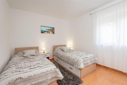 twee bedden in een slaapkamer met witte muren en houten vloeren bij Apartman Galov in Metković