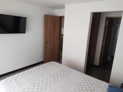 1 dormitorio con 1 cama y TV de pantalla plana en 4 Apartaestudio Cedritos completo, en Bogotá