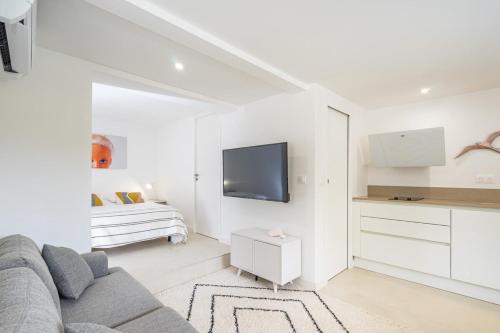 a white living room with a couch and a tv at Giovannina N1 in Cassis