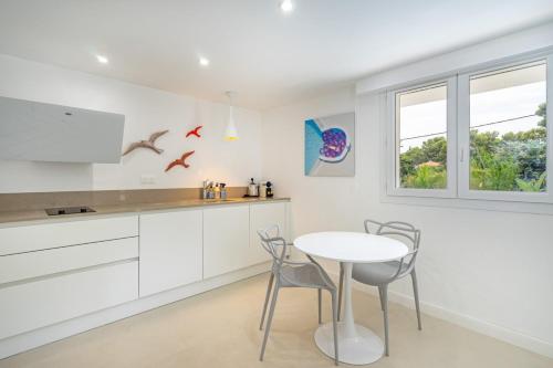 een keuken met witte kasten en een tafel en stoelen bij Giovannina-N1 in Cassis