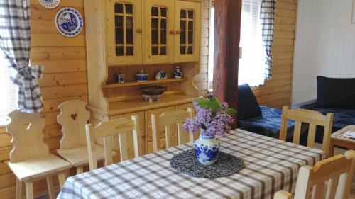 a dining room table with a vase of flowers on it at Sielanówek - Orzechowa Chatka z sauną wanną termalną jacuzzi in Żywiec