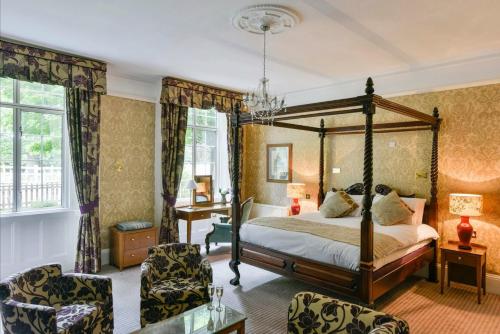 a bedroom with a canopy bed and two chairs at The Charlecote Pheasant in Stratford-upon-Avon