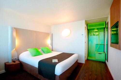 a hotel room with a large bed with green pillows at Campanile Toulouse Sud-Labège innopole in Labège