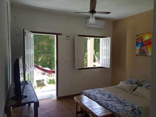 um quarto com uma cama, uma televisão e uma janela em Bahia Mar Pousada - sob nova direção em Arraial d'Ajuda