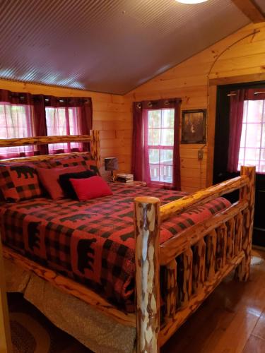 a bedroom with a wooden bed in a cabin at The Riverside - An Amish Built Log Cabin in Genoa
