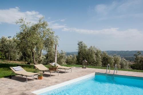 a swimming pool with two lounge chairs next to at Borgo Montefreddo Toscana in San Casciano dei Bagni