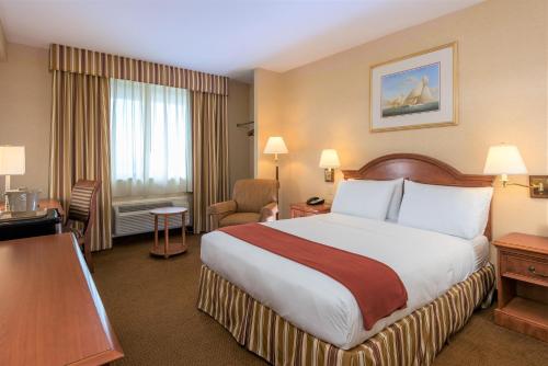una camera d'albergo con un grande letto e una scrivania di Five Towns Inn - JFK Airport a Lawrence