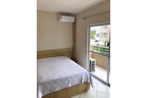 um pequeno quarto com uma cama e uma varanda em Residencial Gaivotas 05 - 1 Quartos - Completo 30m da praia em Florianópolis