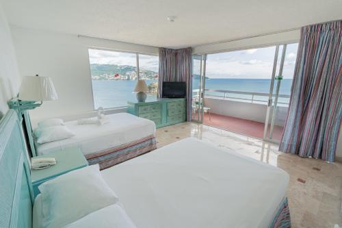 a hotel room with two beds and a view of the ocean at Playa Suites Acapulco in Acapulco