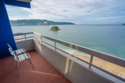 a chair sitting on a balcony looking out at the water at Playa Suites Acapulco in Acapulco