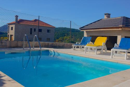 a swimming pool with two blue and yellow chairs at Getaway Home in Bilhó