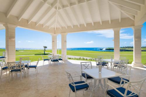 a pavilion with tables and chairs and the ocean at Tortuga Bay in Punta Cana