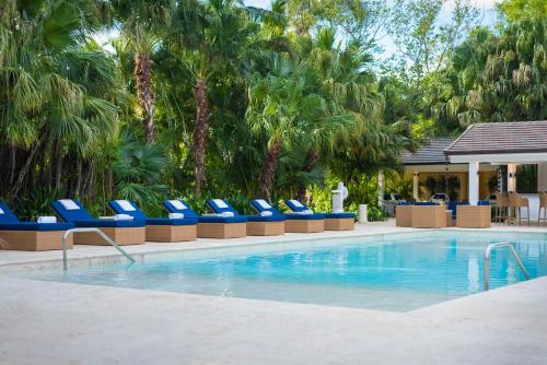 a swimming pool with blue lounge chairs and palm trees at Tortuga Bay in Punta Cana