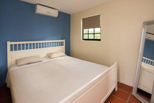 a bedroom with a white bed and a window at Smileys Apartment in Willemstad