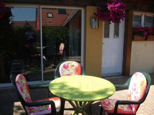 a table and two chairs with a green table and two chairs at Gîtes de Charme Chez Christine in Ottrott