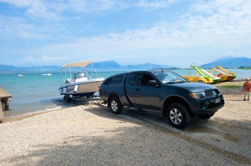 a truck parked on a beach with a boat at San Francesco Camping Village in Desenzano del Garda