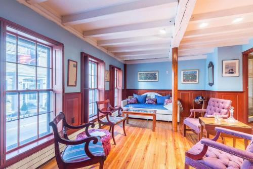 een woonkamer met blauwe muren en een bed en stoelen bij Rockmere Inn in Marblehead