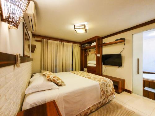 um quarto de hotel com uma cama e uma televisão em Bangalo-Yacamim Praia do Curral em Ilhabela