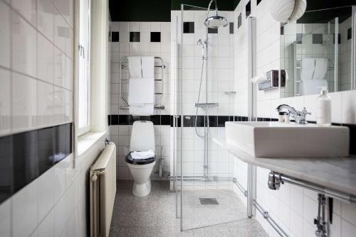 a white bathroom with a toilet and a sink at The Vault Hotel, WorldHotels Crafted in Helsingborg