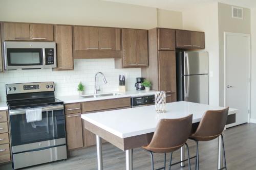 a kitchen with wooden cabinets and a white counter top at Sleepover Premier Downtown Des Moines Apartments in Des Moines