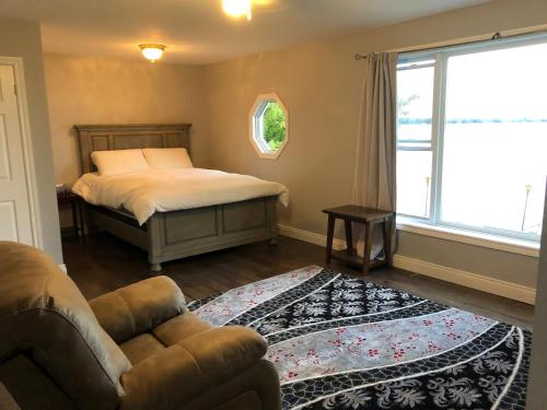 a bedroom with a bed and a couch and a window at Entire waterfront cottage in carrying place in Carrying Place