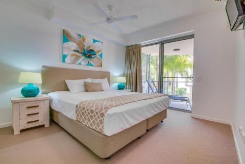a bedroom with a large bed and a balcony at Coolum At The Beach in Coolum Beach