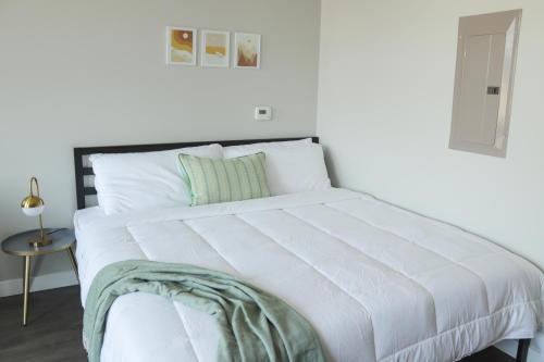 a white bed with a green blanket on top of it at Sleepover Premier Downtown Des Moines Apartments in Des Moines