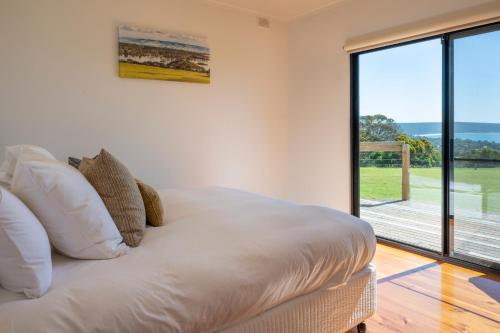 a bedroom with a bed and a large window at Antechamber Bay Retreats in Penneshaw