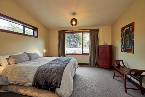 um quarto com uma cama, uma janela e uma cadeira em Glencree Luxury Chalets em Kaikoura