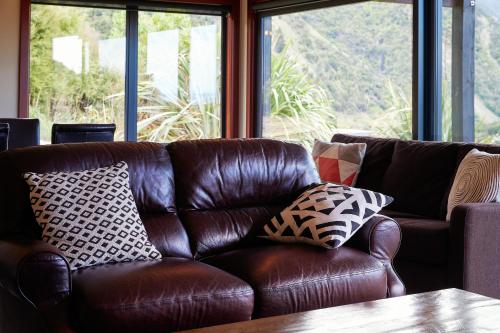 a brown leather couch sitting in a room with windows at Glencree Luxury Chalets in Kaikoura